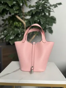 Détail de sac seau en cuir rose montrant texture premium et quaterie de cadenas.