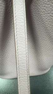 Detailopname van de getextureerde lederen tas met fijne stiksels en zorgvuldige afwerking.