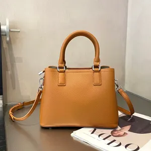 Brown leather handbag detail showing top handle, texture, and metallic hardware finish.