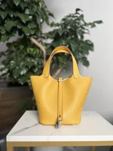 Sac seau jaune en cuir véritable pour femme, élégant sac à main avec poignées et serrure chic.