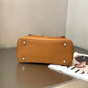 Premium top layer cowhide leather handbag bottom detail display, classic brown tote bag with metal feet.