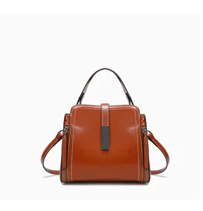 Nahaufnahme einer braunen Lederhandtasche mit Kontrastnähten und Metallverschluss.