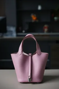 Close-up van de roze lederen emmertas met fijne textuur en het detail van het metalen slot.