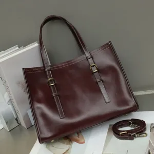 Detailed view of vintage brown leather tote handbag, featuring elegant metal buckle straps.