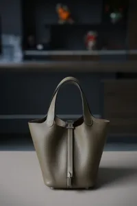 Gedetailleerd overzicht van de lederen emmertas met metalen slot en handvatten, elegante stijl.