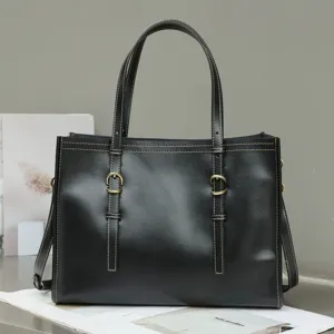 Detailed view of a black leather tote bag with metal buckle and shoulder strap.