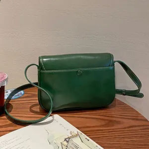 Dunkelgrüne Umhängetasche aus Leder, minimalistische Satteltasche mit Klappe und verstellbarem Riemen.