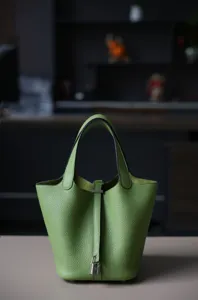 Groene echt lederen emmertas met handvat aan de bovenkant, klassieke minimalistische handtas.