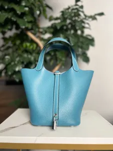 Détails du sac à main seau en cuir bleu, matériau en cuir de vache, serrure en métal élégante.