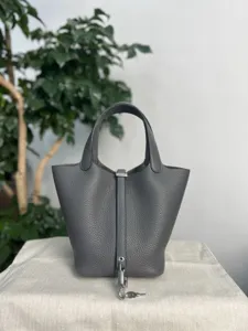 Vue détaillée d'un sac à main seau en cuir gris avec de fines coutures et un cadenas argenté.