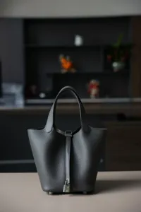 Klassieke echt lederen emmertas voor dames, voorzien van handvatten en een chic hangslot.