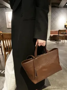 Detailed view of the brown genuine leather tote bag showing soft texture and sturdy handles.