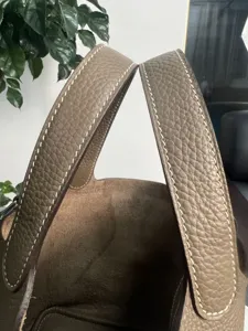 Primo piano dettagliato del manico di borsa in vera pelle con cuciture a contrasto e finitura.