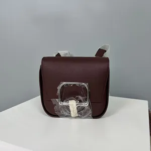 Detail view of the burgundy leather saddle crossbody bag, showing the metal clasp.
