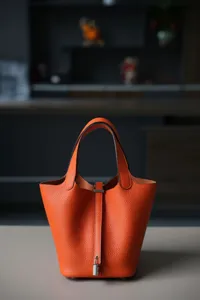 Oranje lederen emmertas shopper tote tas met hangslot hardware, klassieke minimalistische stijl.