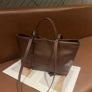 Brown leather tote bag detail view, soft cowhide material, retro style shoulder handbag.