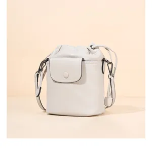 Stylish light grey leather bucket bag with drawstring closure and front flap pocket for women.