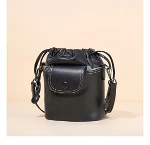 Close-up detail of the black leather bucket bag, showing the drawstring closure and flap.