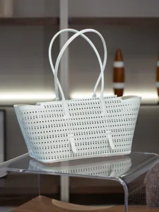 Vue détaillée d'un élégant sac cabas en cuir blanc perforé avec deux poignées.