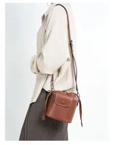 Stylish brown leather bucket bag with drawstring and flap closure, perfect for daily commute.