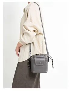 Detail shot of grey genuine leather bucket bag with drawstring and front flap pocket design.