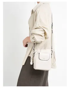 Detail view of the beige leather bucket bag showcasing drawstring and front flap pocket.