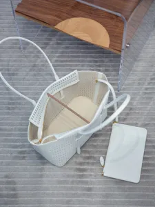 Vue détaillée du sac cabas en cuir perforé blanc avec pochette assortie et quincaillerie.