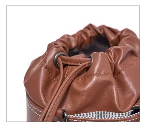 Close-up detail of brown leather bucket bag featuring drawstring closure and metal eyelets.