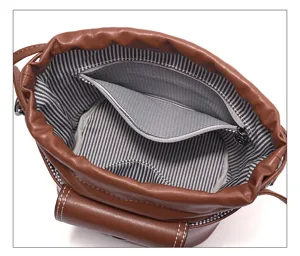 Detailed view of brown leather bucket bag interior, striped lining, zipper pocket.