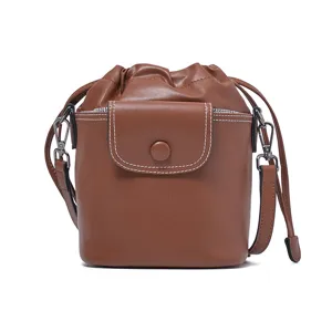 Brown leather drawstring bucket bag with front flap pocket and stylish shoulder strap.