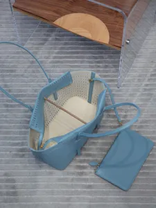 Gros plan sur le sac cabas en cuir perforé bleu clair, montrant le motif ajouré élégant.