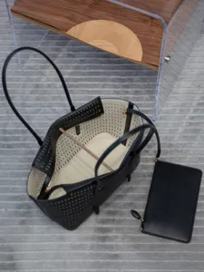 Détail de cabas en cuir noir perforé avec intérieur en velours et pochette assortie.