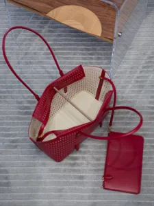 Vue détaillée d'un sac cabas rouge en cuir perforé avec de longues anses et une pochette.
