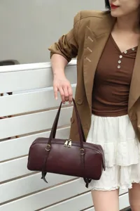 Vintage genuine leather cylindrical shoulder bag for women, chic brown underarm baguette bag.
