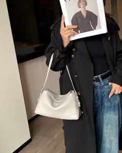 Dettaglio ravvicinato di borsa a spalla in pelle grigia chiara con texture morbida.