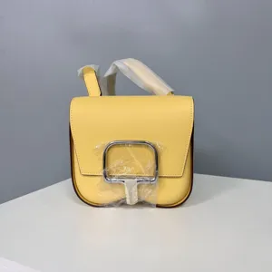 Yellow leather mini saddle crossbody bag detail view showing fine grain texture and metallic clasp.