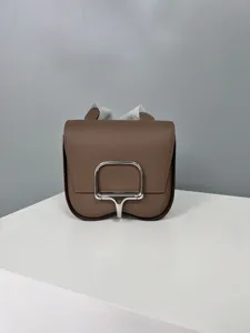 Close-up detail of the brown leather mini shoulder bag featuring a sleek silver metal clasp.