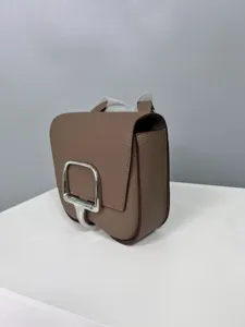Detail view of the elegant brown leather crossbody saddle bag featuring silver metal clasp.