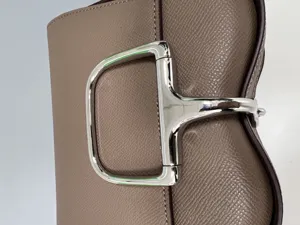 Close up detail of luxury style leather shoulder bag with prominent metal horsebit clasp hardware.