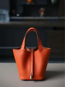 Premium oranje lederen emmertas met metalen slot hardware en dubbele handgrepen.