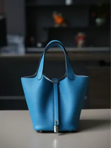 Klassieke blauwe lederen emmertas met handvatten en metalen slot voor dagelijks gebruik.