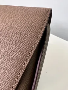 Close-up detail of genuine leather saddle bag flap, showing fine pebbled grain and stitching.