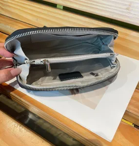 Detailed view of black genuine leather clutch wallet interior, showing zipper pocket and lining.