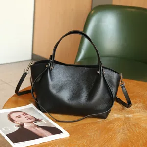 Black genuine leather tote bag detail, natural soft pebble grain, elegant shoulder strap.
