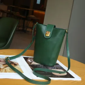 Green leather bucket bag with metal clasp and shoulder strap for women daily wear.