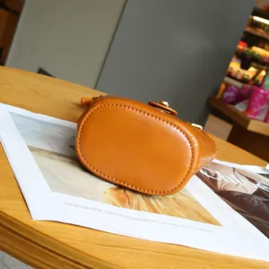 Detailed view of brown leather mini bucket phone bag, top-grain cowhide texture and stitching.