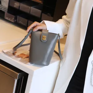 Detailed grey leather bucket cross body bag showcasing elegant golden lock and slim strap.