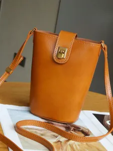 Minimalist vegetable-tanned leather crossbody bucket bag, stylish small shoulder bag for women.