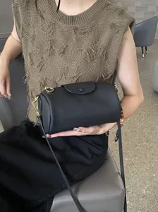 Detail view of black genuine leather cylinder crossbody bag, soft cowhide shoulder purse.