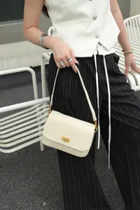Classic cream leather underarm shoulder bag with metal turn-lock closure and slim strap.